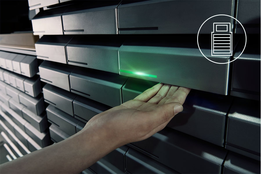 Hand eines Nutzers aktiviert ein automatisches Werkzeugausgabesystem mit beleuchteter Schublade