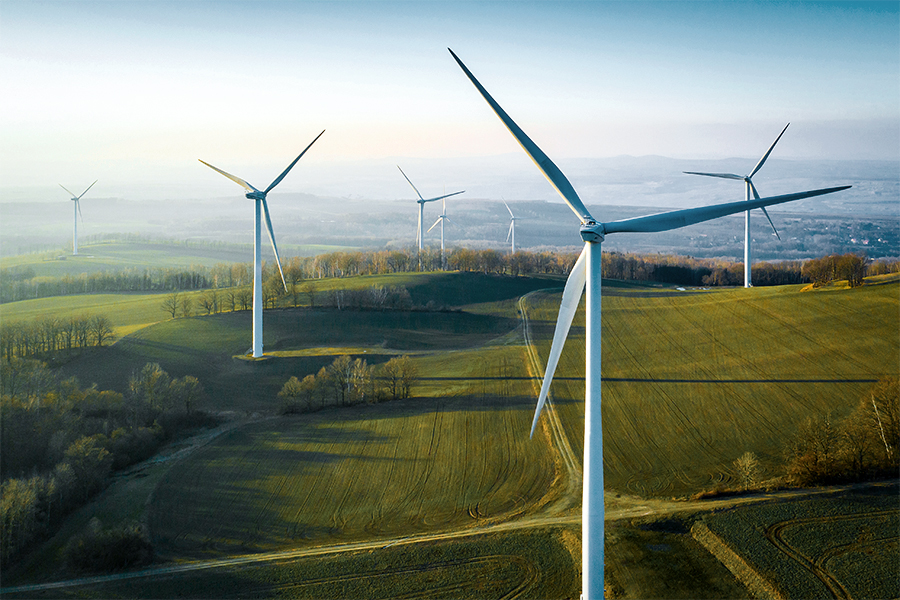Wind turbines in an open field with rolling hills in the background