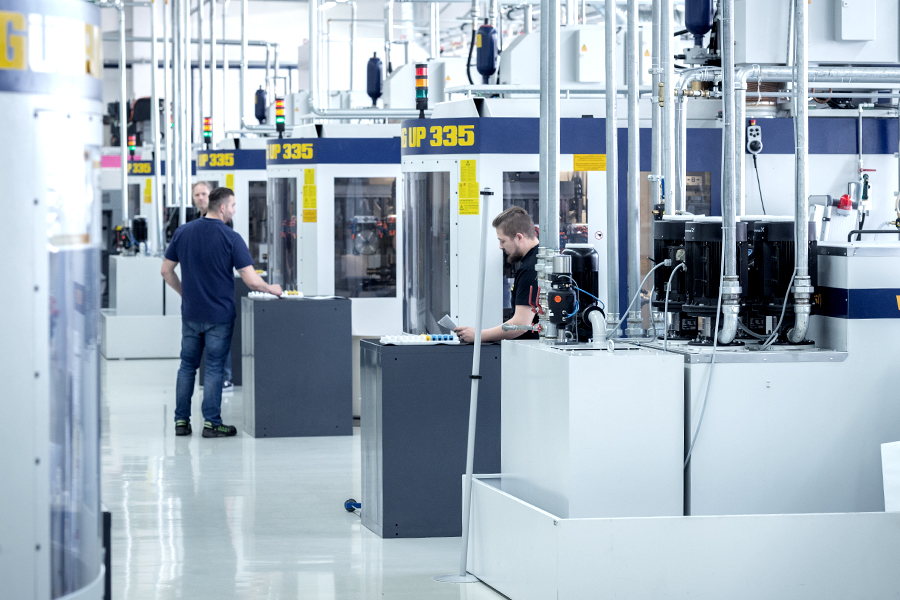 Mitarbeiter bedienen hochmoderne CNC-Maschinen in einer hell beleuchteten, geräumigen Fabrikhalle von Gühring
