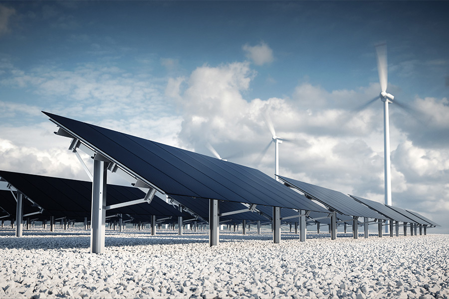 Solar modules in the foreground and wind turbines in the background in a snowy landscape