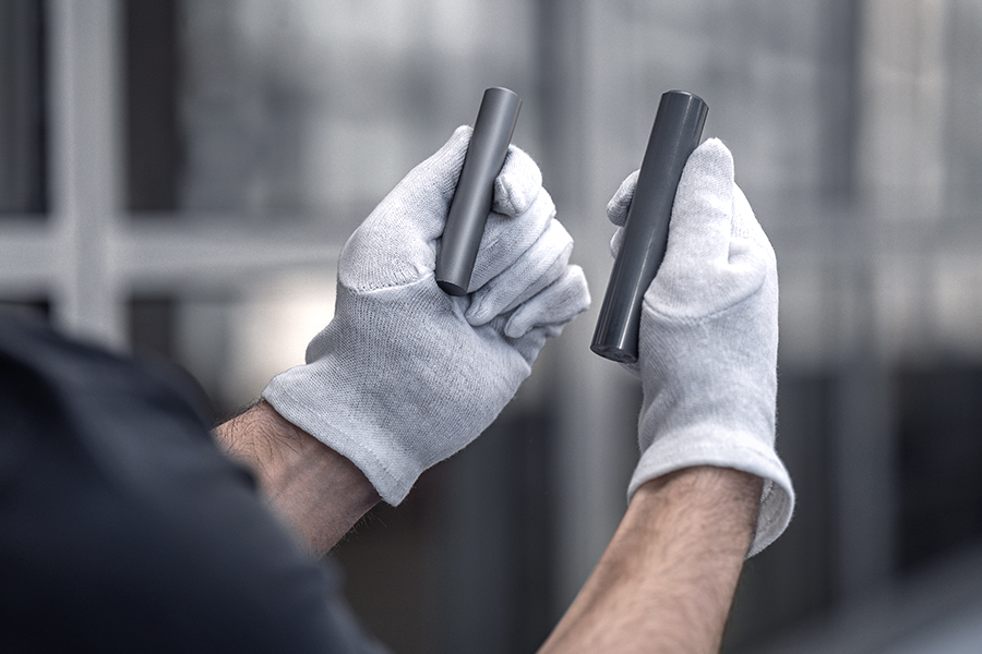 A person wearing gloves inspects 2 metal rods
