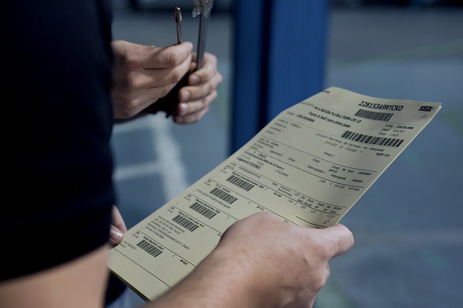 Mitarbeiter hält Präzisionswerkzeuge und einen Arbeitsauftrag in der Hand