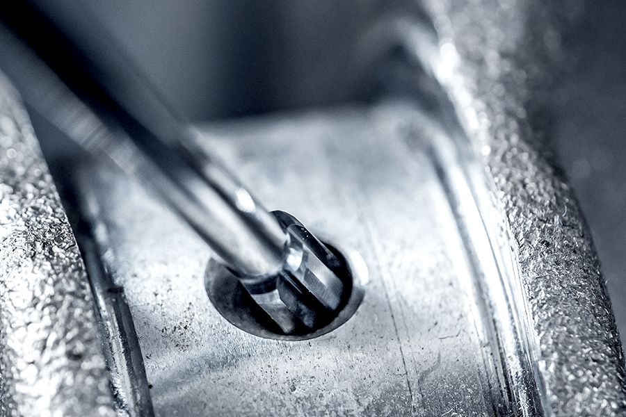 Close-up of a manual deburring tool used to smooth a metal edge