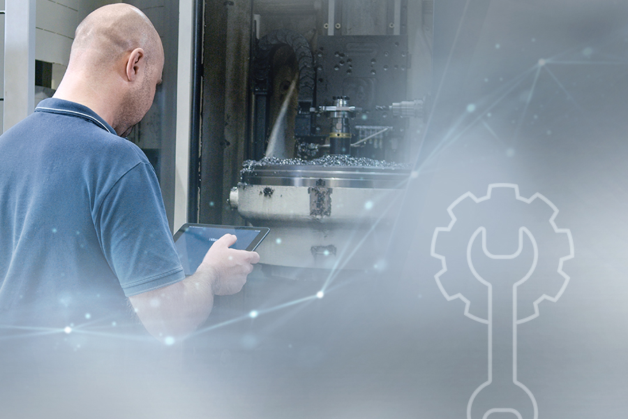 A skilled worker in mechanical engineering operates a CNC machine and uses a tablet for process control