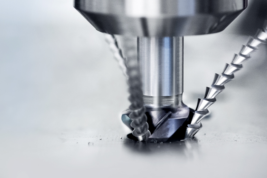 Close-up of a high-precision, coated drilling tool during the machining process, with metal chips visible
