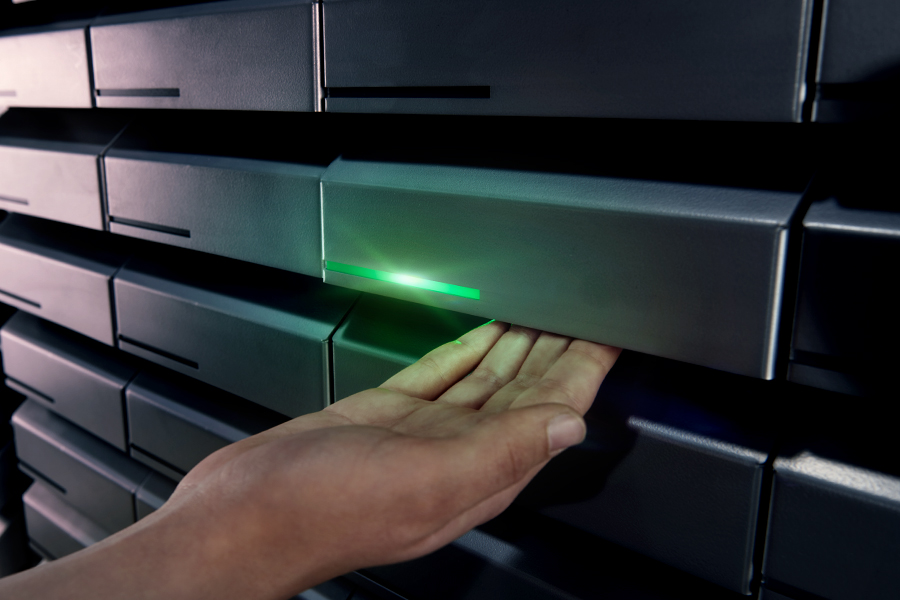 Hand eines Technikers, die ein Werkzeug aus einem automatisierten Werkzeugausgabesystem mit grüner Leuchtanzeige entnimmt