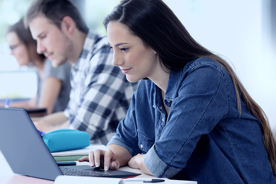 Junge Mitarbeiter in einem modernen Lernumfeld, konzentriert am Arbeiten auf ihren Laptops