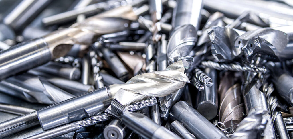 Ein großer Haufen von gebrauchten Metallwerkzeugen und Schneidwerkzeugen auf einem Tisch, die für das Recycling und die Wiederverwendung in der Kreislaufwirtschaft bereit sind