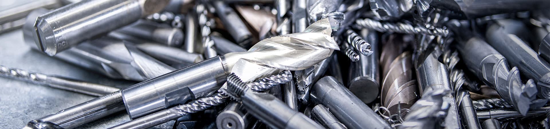 Ein großer Haufen von gebrauchten Metallwerkzeugen und Schneidwerkzeugen auf einem Tisch, die für das Recycling und die Wiederverwendung in der Kreislaufwirtschaft bereit sind