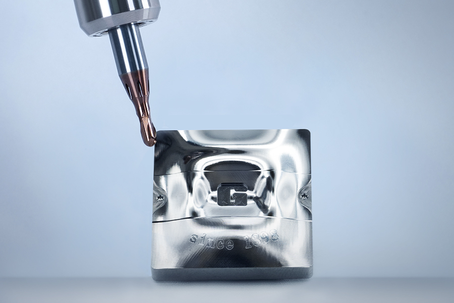 Detailaufnahme beim Präzisionsbearbeiten eines metallischen Bauteils mit eingeprägtem 'G-Mold' Logo