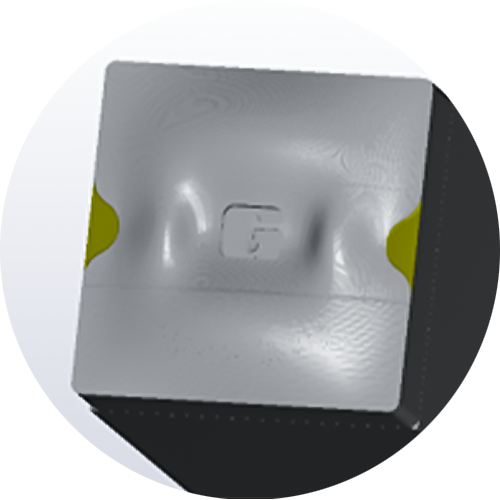 Detailaufnahme eines grauen metallischen Würfels mit seitlichen gelben Markierungen, auf dem das Logo 'G' eingraviert ist Detailaufnahme eines grauen metallischen Würfels mit seitlichen gelben Markierungen, auf dem das Logo 'G' eingraviert ist