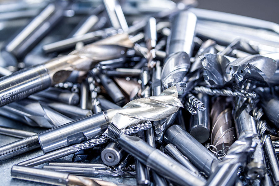 Pile of recycled, heavily worn metal tool parts and pieces, mainly drills and milling cutters