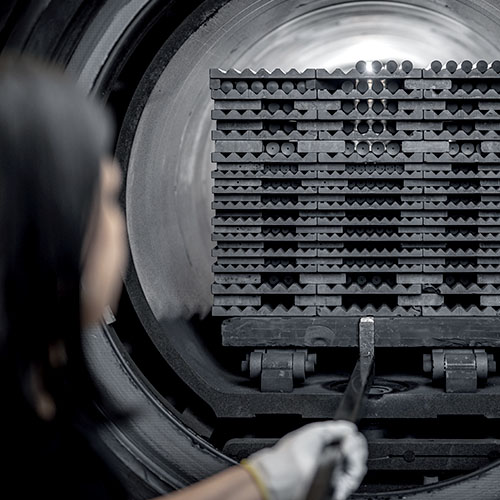 Industriearbeiter überwacht den Sinterprozess von metallischen Werkstücken in einem Hochtemperatur-Ofen