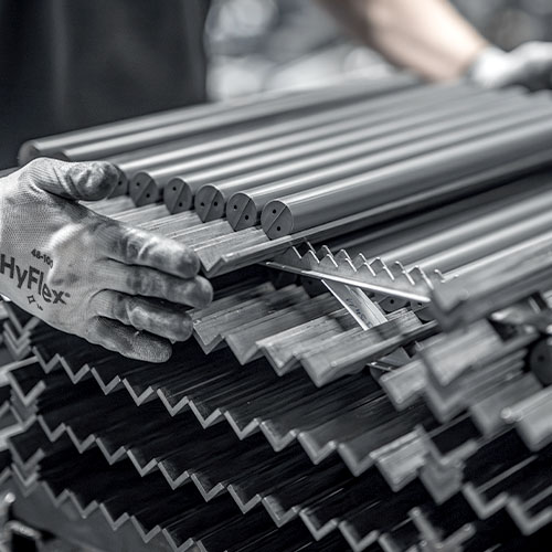 Industriearbeiter überprüft Metallstäbe, die nach dem Kneten und einer streng kontrollierten Trocknung in Klimakammern sortiert werden