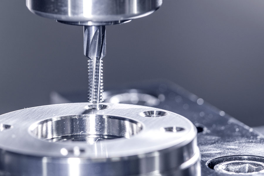 Thread milling cutter during precision machining of a metal component, whereby clean threads are produced in a CNC machine.