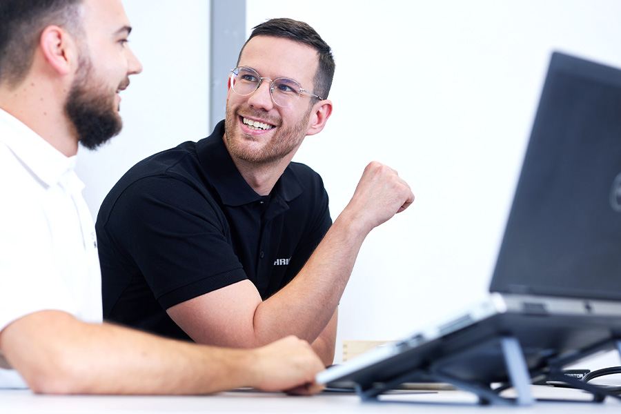 Two colleagues in conversation while working together on a laptop