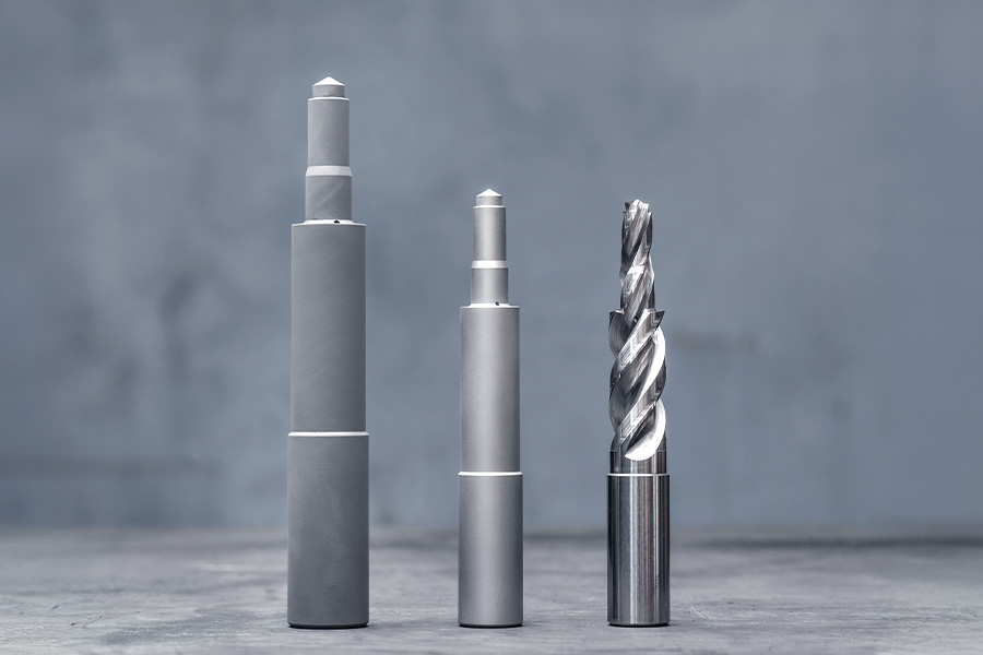 Three production stages of a solid carbide drill bit: pressed blank, sintered blank and finished tool in industrial machining