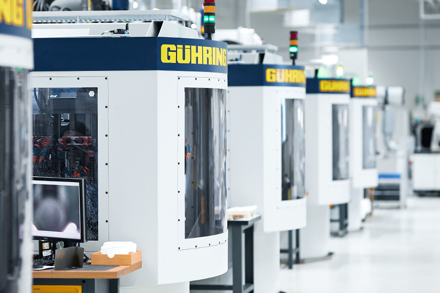 View of a modern production hall with a row of CNC machines and a worker monitoring the production
