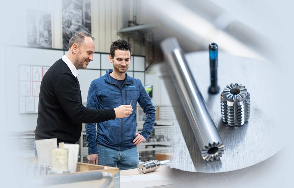 Zwei Männer stehen in einer Fertigung, daneben das Werkzeug der modulare Gewindeformer