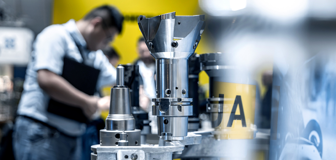 High-precision cutting tools at a trade fair – focus on metal tool holders, with technical visitors in the background engaged in consultation.