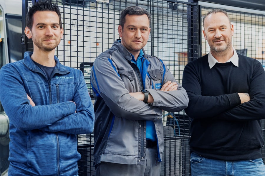 Drei Männer stehen mit gekreuzten Armen in einer Produktion